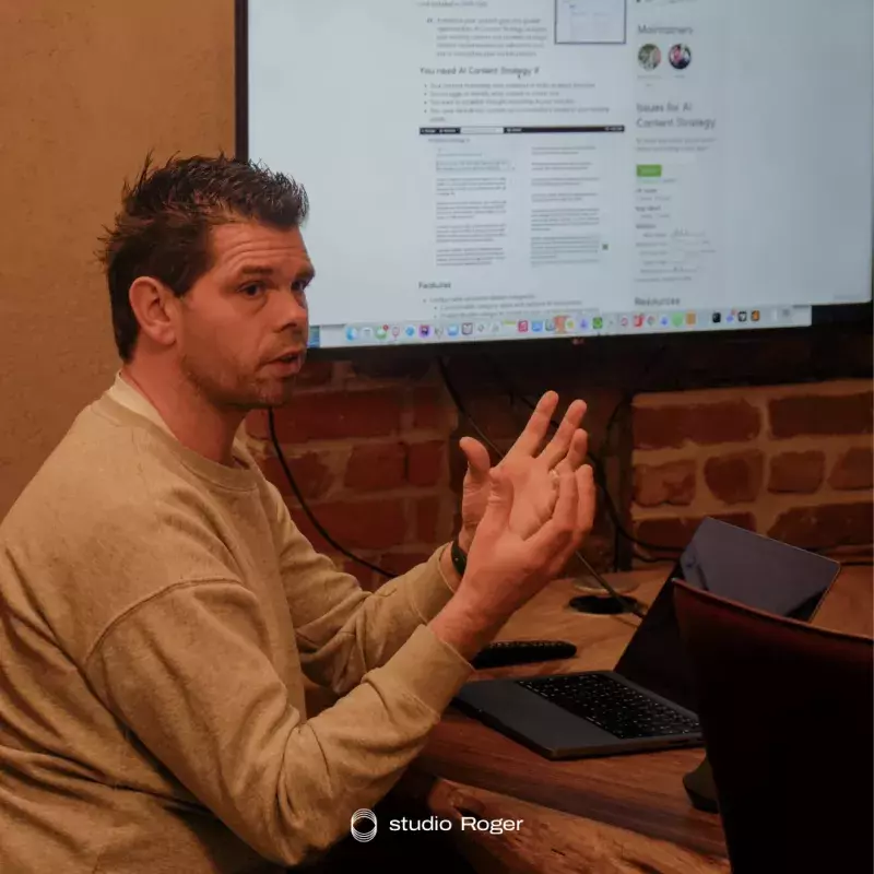 Man geeft presentatie met laptop en scherm in vergaderruimte.